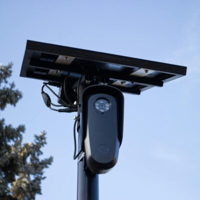 A solar-powered outdoor surveillance camera mounted on a pole, capturing clear day images.